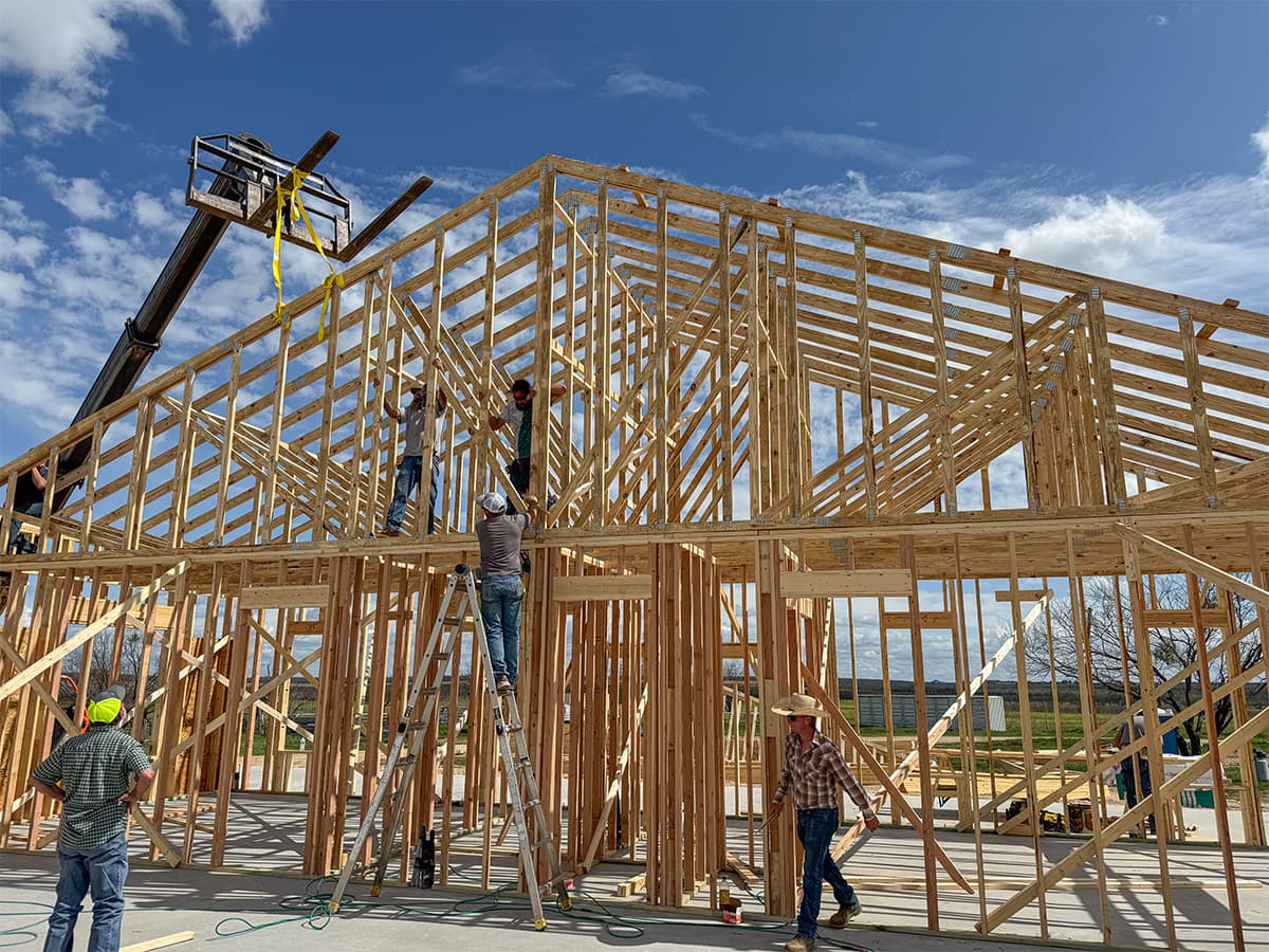 Construction workers installing roof trusses with a telescoping forklift